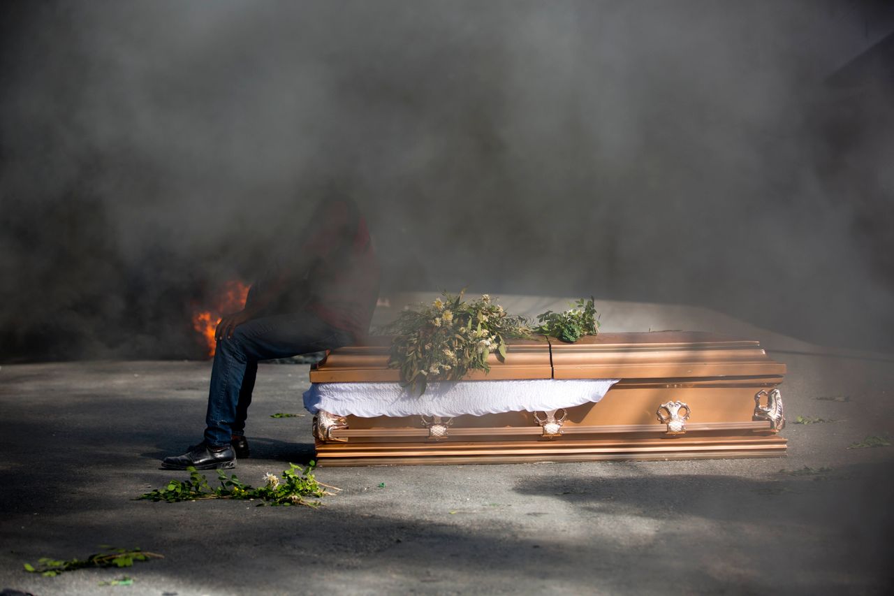 A demonstrator sits on the coffin containing the body of a protester who was killed during previous protests in Port-au-Prince, Haiti, Monday, March 4, 2019. Protesters are angry about skyrocketing inflation and the government's failure to prosecute embezzlement from a multi-billion Venezuelan program that sent discounted oil to Haiti.