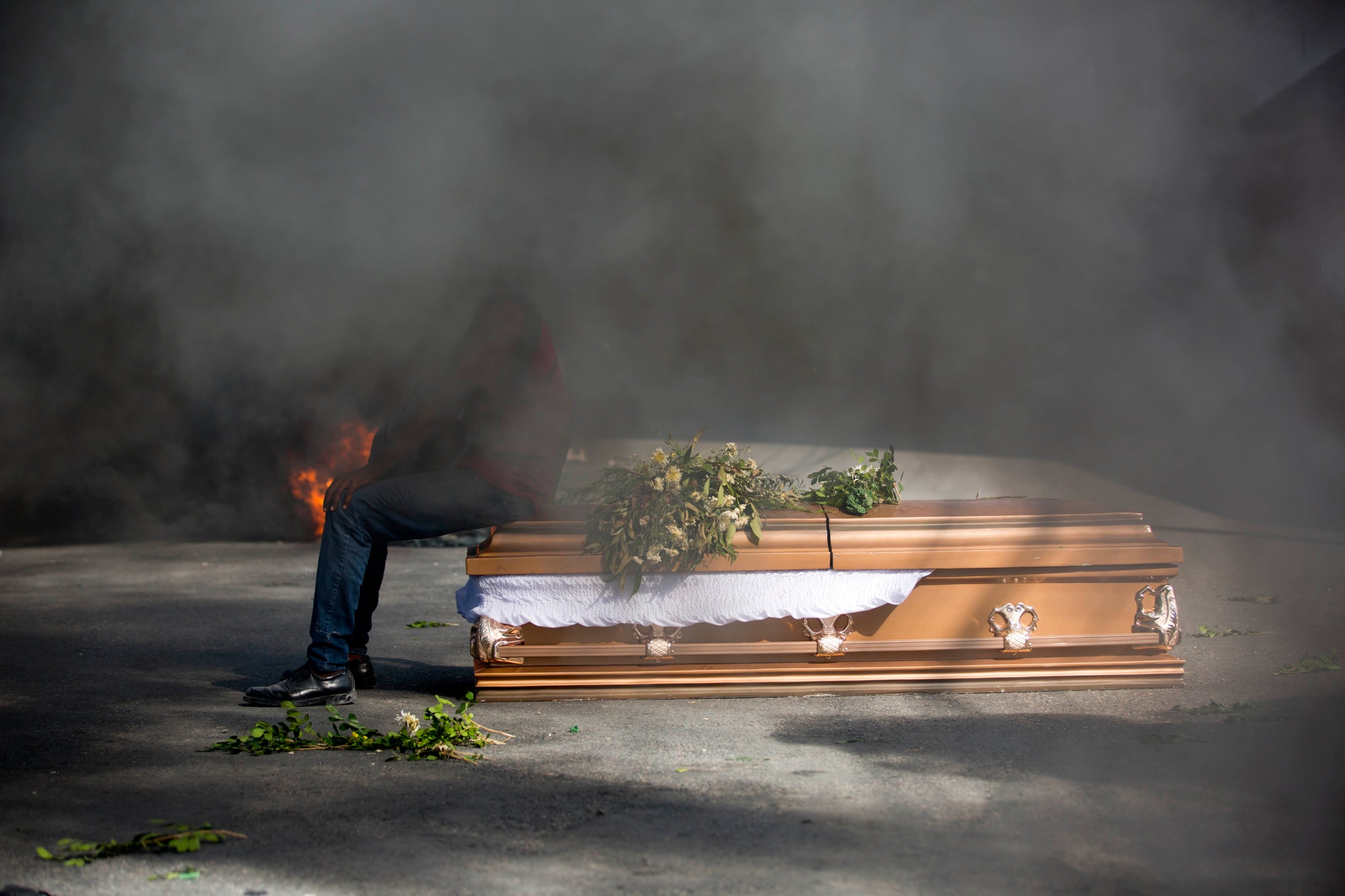A demonstrator sits on the coffin containing the body of a protester who was killed during previous protests in Port-au-Princ