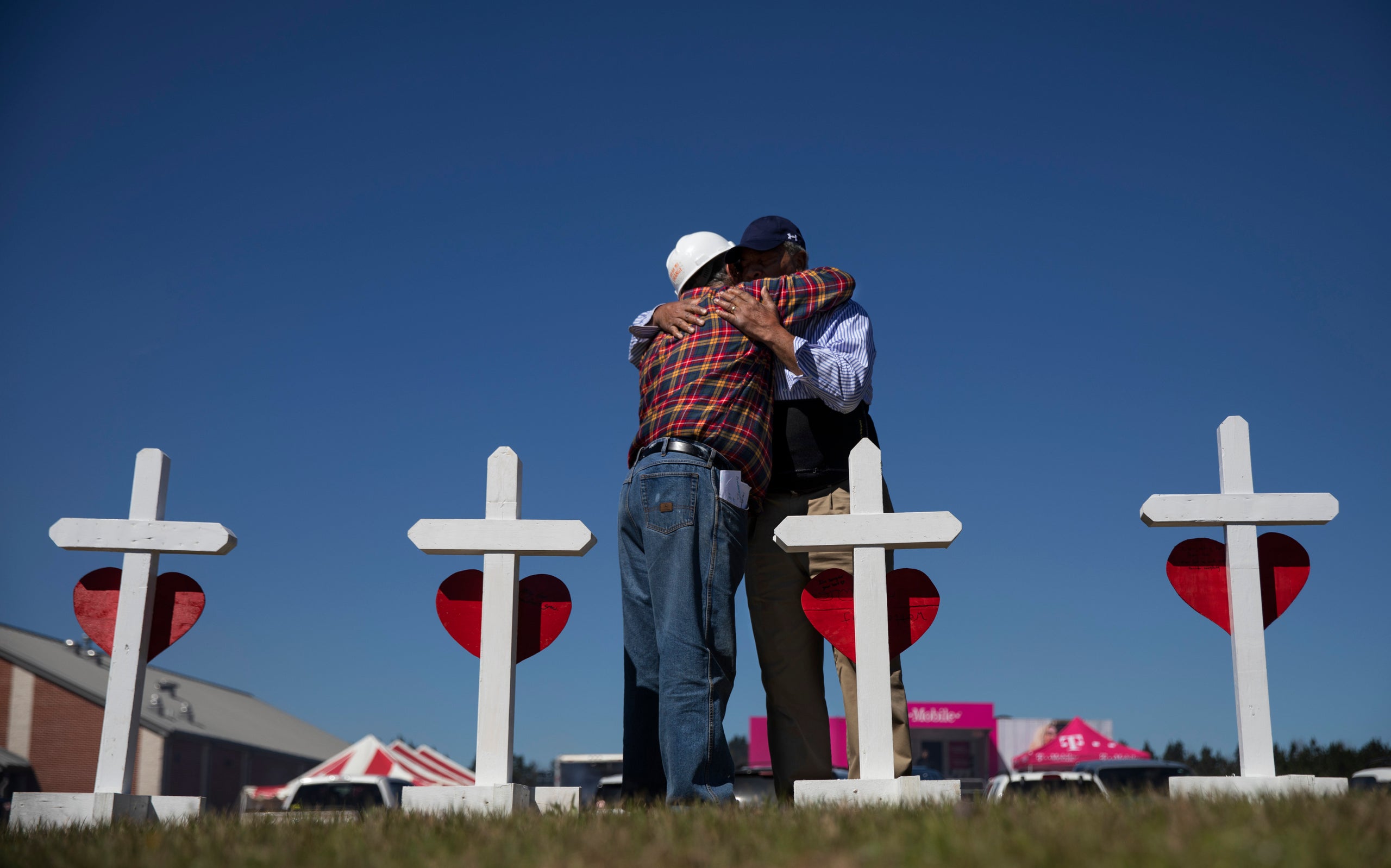 Rev. Arthur Thomas, right, of Mt. Nebo Baptist Church, is embraced by Greg Zanis, who built a cross for each victim of the to