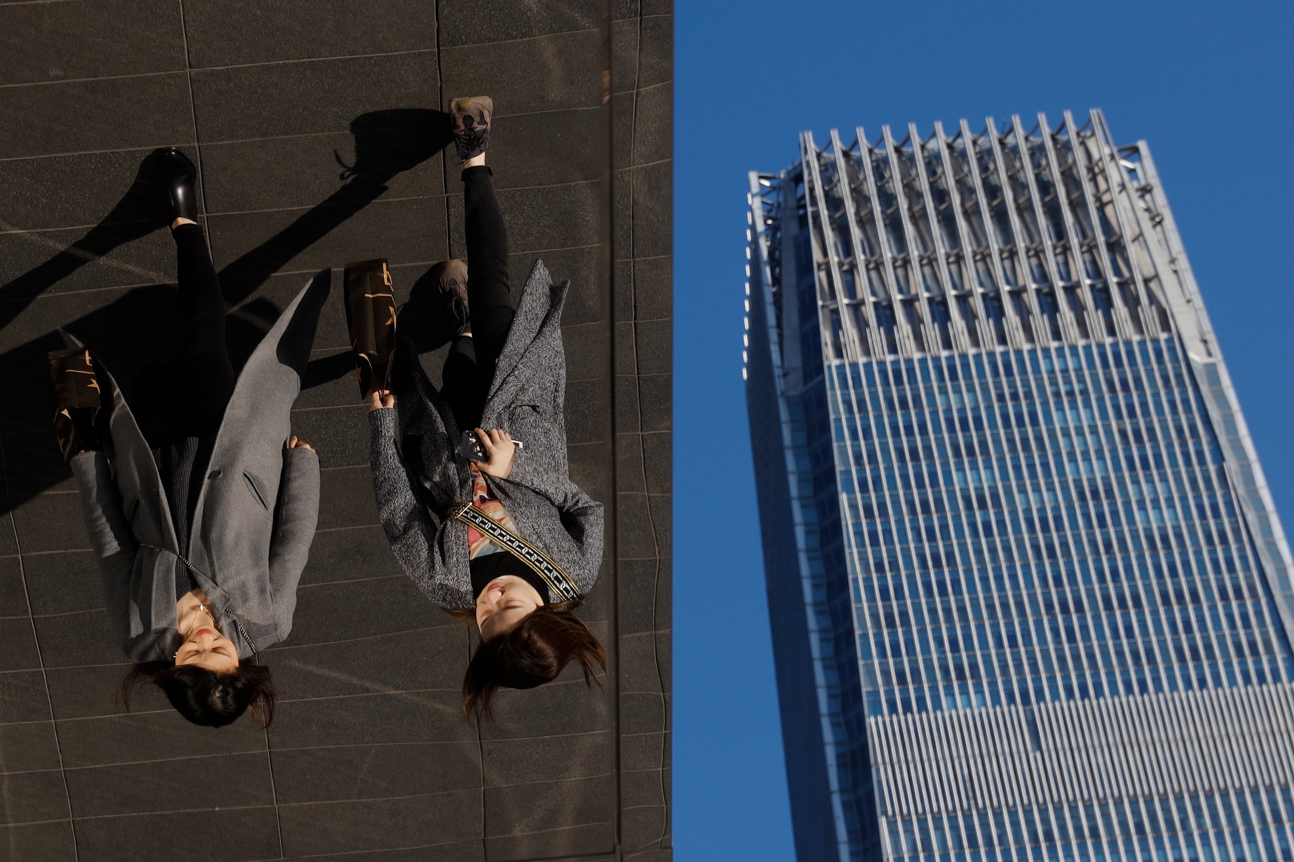In this March 6, 2019, photo, women are reflected on silver panels of the French luxury brand Louis Vuitton flagship store at