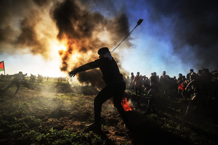 A Palestinian throws a stone with a slingshot toward Israeli security forces during the "Great March of Return" demonstration
