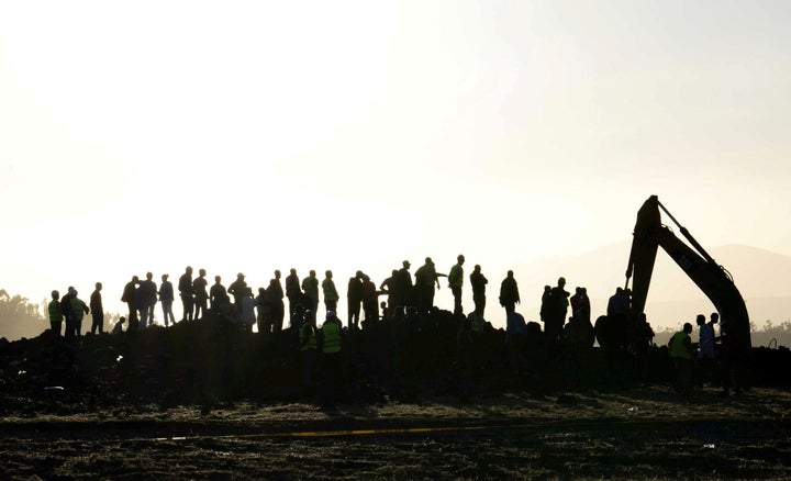 People watch as a tractor excavates the scene of the Ethiopian Airlines Flight ET 302 plane crash, near the town of Bishoftu, southeast of Addis Ababa, Ethiopia.