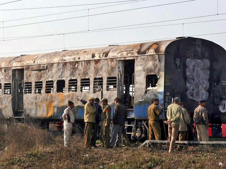 Police officers in front of charred train after explosion on Samjhauta Express.