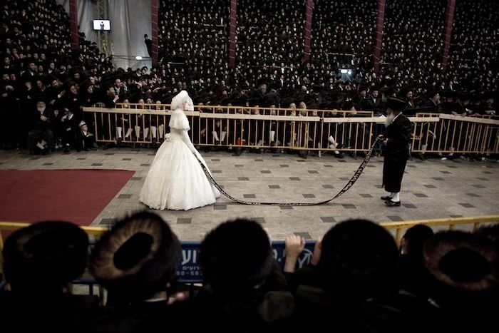 Miles de judíos jasidistas observan a un hombre judio ultraortodoxo que baila con la novia