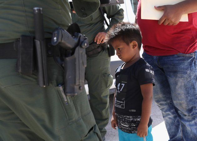 Un niño y su padre, custodiados cerca de la frontera entre México y EEUU.