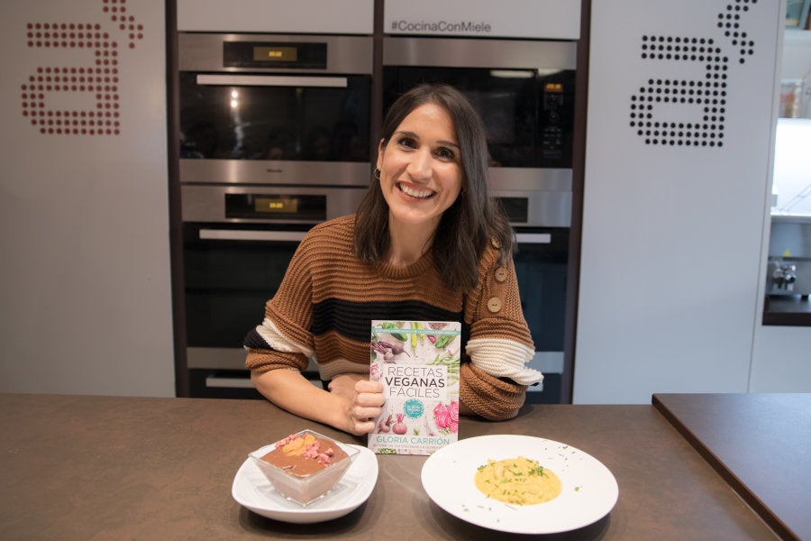 Gloria Carrión posa con dos de sus platos y su libro 'Recetas veganas fáciles' en la librería gastronómica A punto (Madrid).