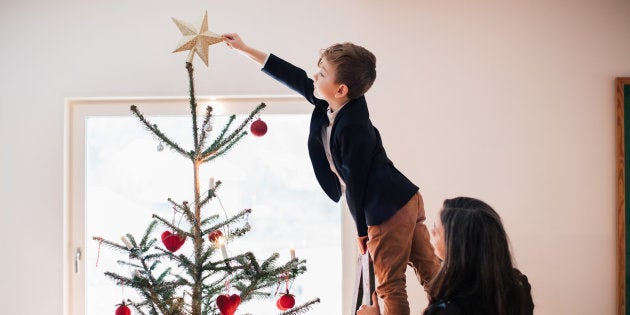 Un niño coloca la estrella en el árbol de Navidad.