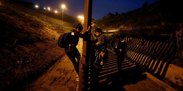 Migrantes de honduras tratan de saltar la valla que separa México y Estados Unidos.