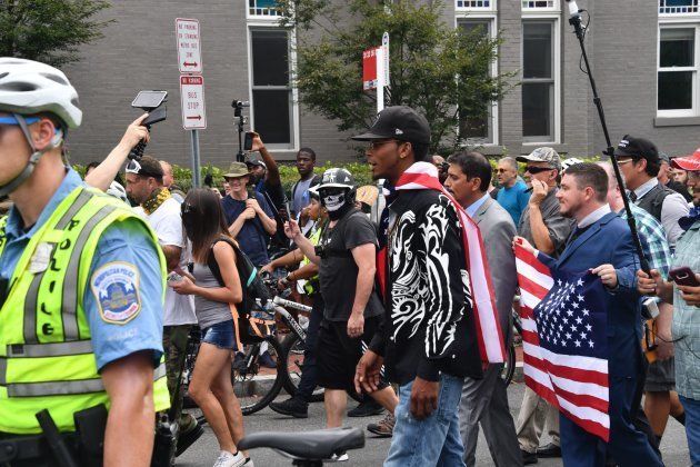 El organizador de la marcha racista Jason Kessler sostiene una bandera de EEUU rodeado de allegados