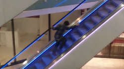 Un borracho intenta subir las escaleras mecánicas ante la