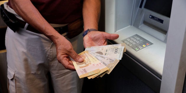 Un hombre enseña los bolívares que ha retirado de un cajero en Caracas el marzo.