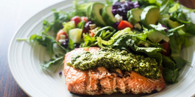 Plato casero de salmón al pesto y ensalada de lechuga con aguacate, pepino, tomate, zanahoria y col morada.