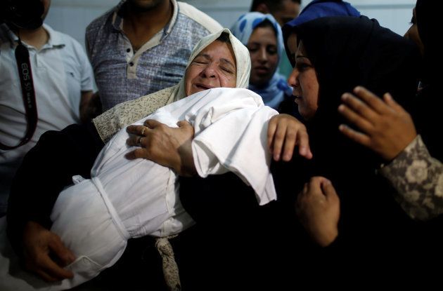 Una allegada llora desconsolada mientras abraza el cadáver de la niña, durante su funeral en Gaza capital.