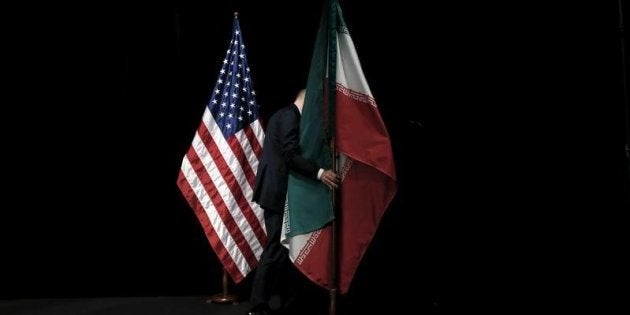 Un empleado retira las banderas de EEUU e Irán tras la firma del acuerdo sobre el programa atómico de Teherán, escenificada en Viena el 14 de julio de 2015.
