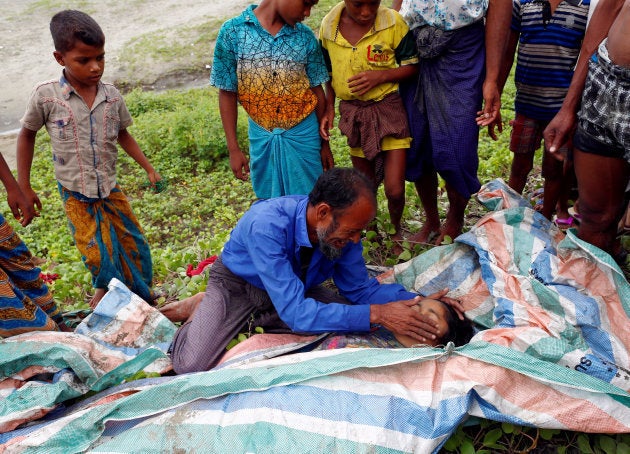 Un hombre llora mientras acaricia el rostro de su hija muerta, tras cruzar por el río que hace frontera entre Birmania y Bangladesh.