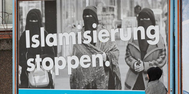 Una mujer pasa junto a un cartel electoral de AfD contra la inmigración en Alemania.