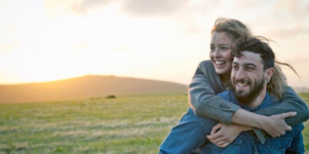 Happy young couple in rural field, Dorset, England