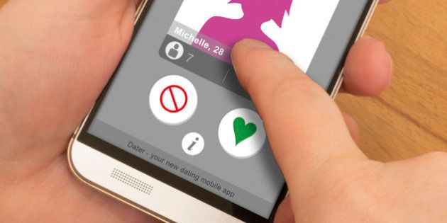 Holding a smartphone in one hand, swiping or using gesture control with the other hand. On the screen is a mock up of a dating app with a female profile.
