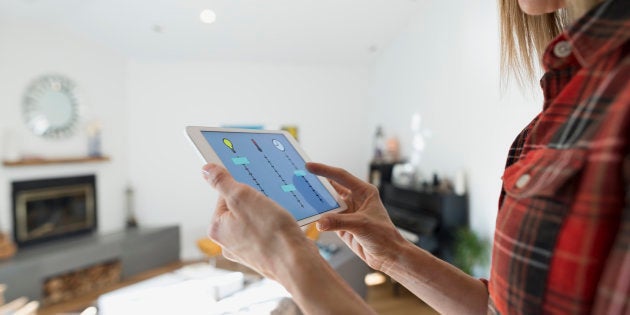Woman controlling home utilities with digital tablet