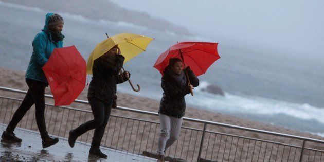 Tres mujeres se protegen de la lluvia en el paseo marítimo de A Coruña, el pasado