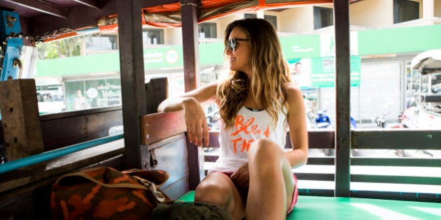 A woman riding in an open air taxi while on vacation in Thailand.