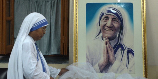 TOPSHOT - A nun of ?the Missionaries of Charity decorates a picture of Mother Teresa prior to a special prayer service at Mother House in Kolkata on December 18, 2015. Mother Teresa, set to become a saint after the Vatican announced recognition of her second miracle, became a global symbol of compassion for her care of the sick and destitute. / AFP / DIBYANGSHU SARKAR (Photo credit should read DIBYANGSHU SARKAR/AFP/Getty Images)