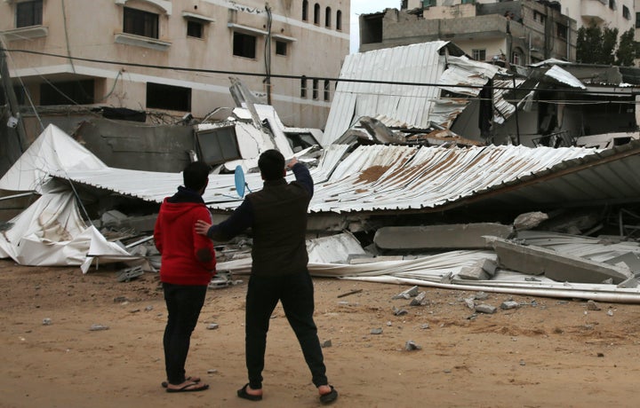 Palestinians inspect a damaged building that belonged to the Hamas ministry of prisoners.