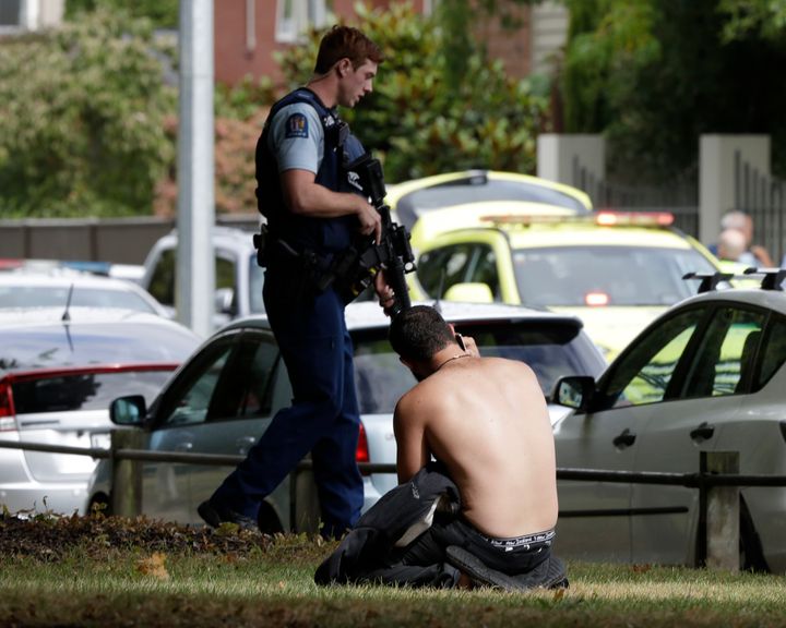 A man rests on the ground as he speaks on his mobile phone across the road from mosque in central Christchurch,