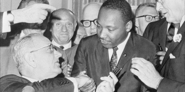 (FILES) US President Lyndon Johnson (l) shakes hands with the US clergyman and civil rights leader Martin Luther KIng (c) 03 July 1964 in Washington DC, after handing him a pen during the ceremonies for the signing of the civil rights bill at the White House. Martin Luther King was assassinated on 04 April 1968 in Memphis, Tennessee. James Earl Ray confessed to shooting King and was sentenced to 99 years in prison. King's killing sent shock waves through American society at the time, and is still regarded as a landmark event in recent US history. (Photo credit should read -/AFP/Getty Images)