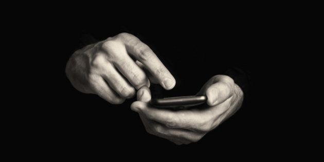 Man typing text message on his smartphone, focus on hands and the phone device.