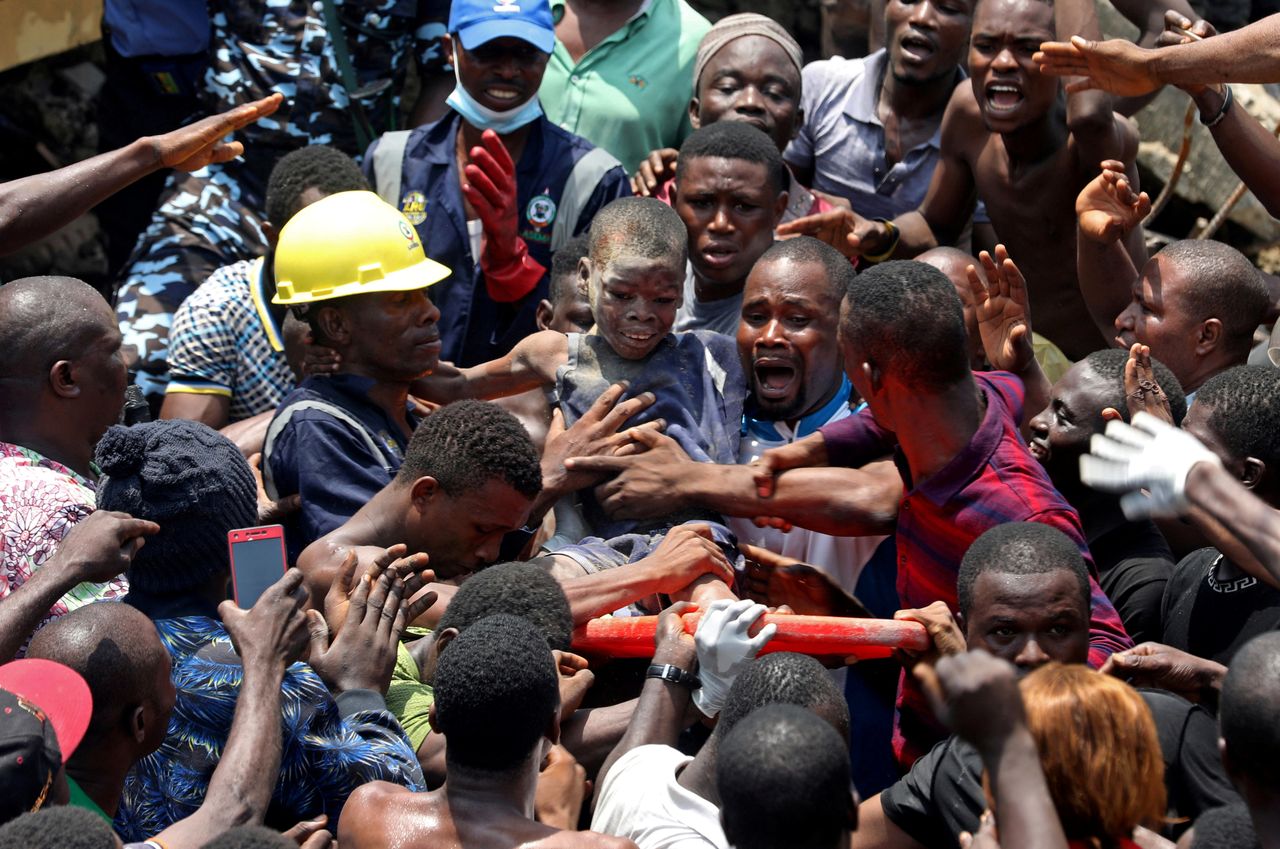 Men carry nine-year-old Ademola Ayanbola, who was rescued at the site of a collapsed building containing a school in Lagos, Nigeria, March 13, 2019.