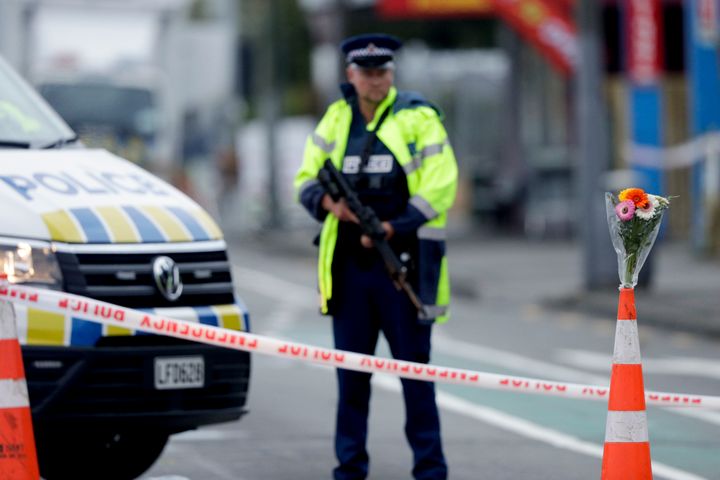 Flower rest at a road block, as a Police officer stands guard near the Linwood mosque, site of one of the mass shootings at two mosques in Christchurch, New Zealand, on Saturday.