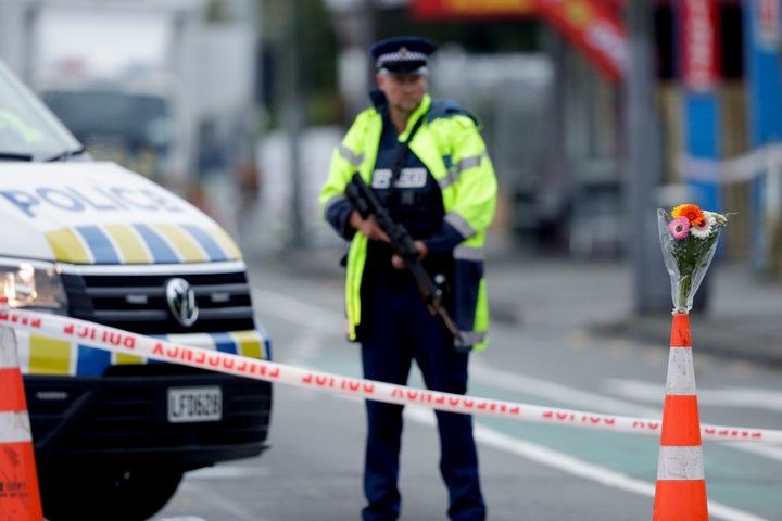 <strong>Flower rest at a road block, as a Police officer stands guard near the Linwood mosque, site of one of the mass shootings at two mosques in Christchurch, New Zealand, on Saturday.</strong>