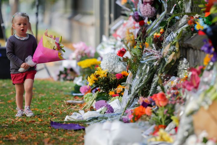 A girl walk to lay flowers on a wall at the Botanical Gardens in Christchurch, New Zealand on Sunday.