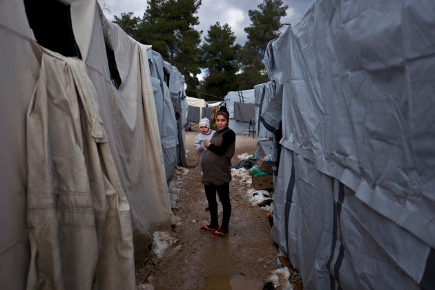 En esta imagen del domingo 1 de enero de 2017, Sa'da Bahjat, de 20 años y embarazada de 9 meses, una refugiada siria de al-Hasaka, sostiene a su hija Yamoor, de 11 meses, mientras posa para una foto a la entrada de su cobertizo en el campo de refugiados de Ritsona, en Grecia.