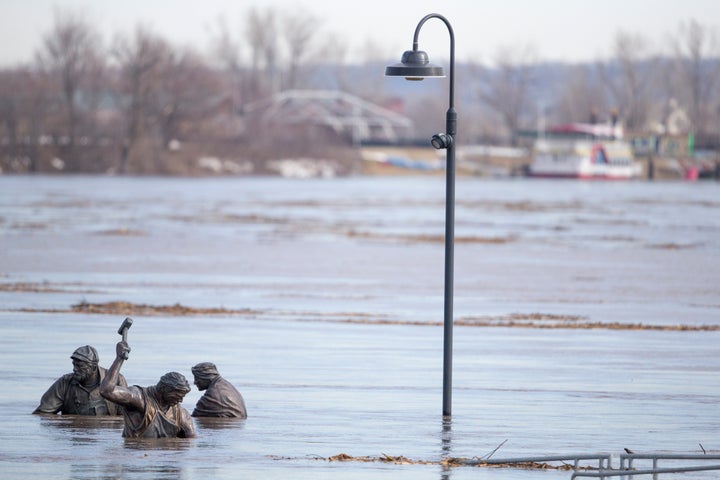 The high waters of the Missouri River almost cover figures in the Monument to Labor statue by Matthew J. Placzek, in Omaha, N