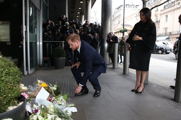 Harry leaving flowers outside the house as Meghan looks on.