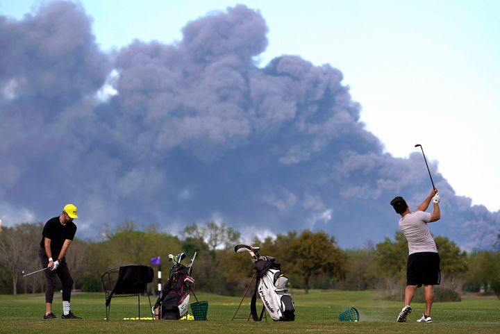 Golfers practice at the Battleground Golf Course driving range as a chemical fire at Intercontinental Terminals Company continues to send dark smoke over Deer Park, Texas, on, March 19, 2019.