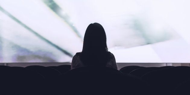 Rear view of woman sitting alone watching movie in empty
