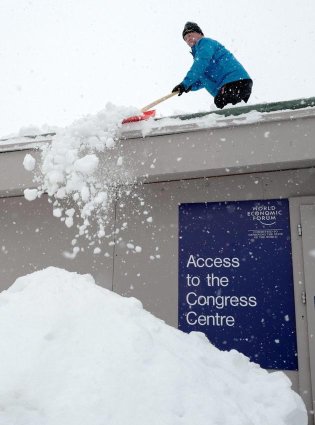 Un homme déblaie la neige d'un toit tout près du centre de congrès de Davos, le 21