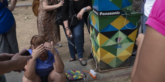 A Caracas, des Vénézuéliens rechargent leurs téléphones mobiles à une station d'énergie solaire pendant...