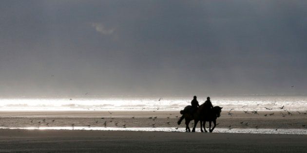 French mounted police officers patrol on the beach during