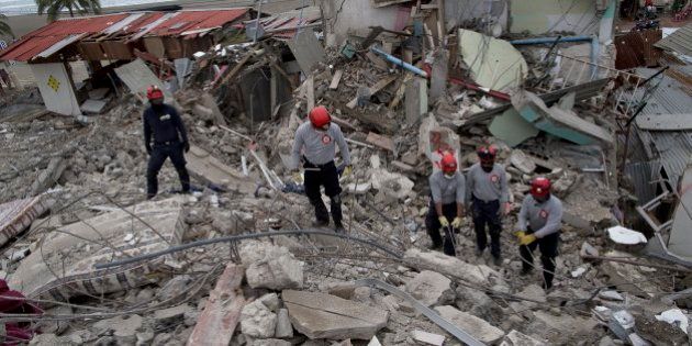Ecuadorean firefighters comb through rubble of buildings destroyed by a 7.8-magnitude earthquake, in...