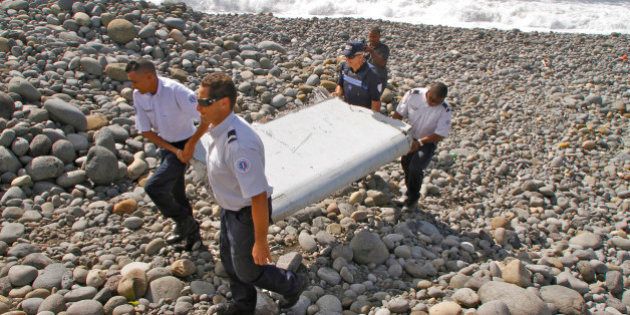 In this photo dated Wednesday, July 29, 2015, French police officers carry a piece of debris from a plane...