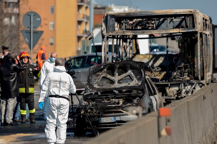 Forensic police and firefighters work by the wreckage of the school bus.