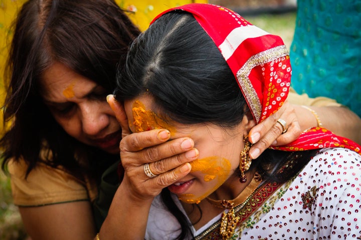 Women during the haldi ceremony, in which people rub turmeric mixtures on the bride and groom to promote bright complexions for their wedding.