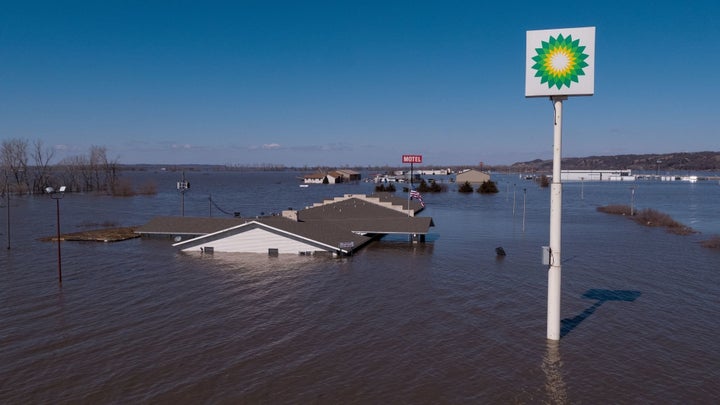 A gas station sign rises above the devastating floodwaters in a Midwest town.