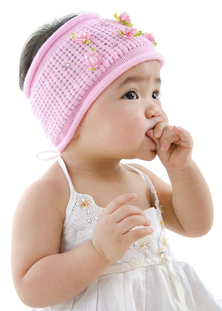 Cute pan Asian baby girl eating on white background