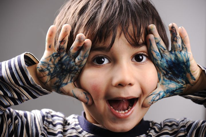 Excited little boy with messy color hands