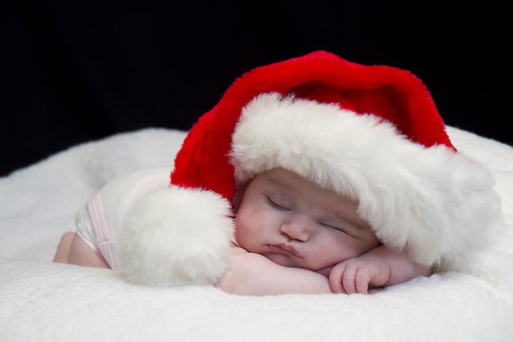 Baby girl wearing red santa hat while sleeping and peeking at times